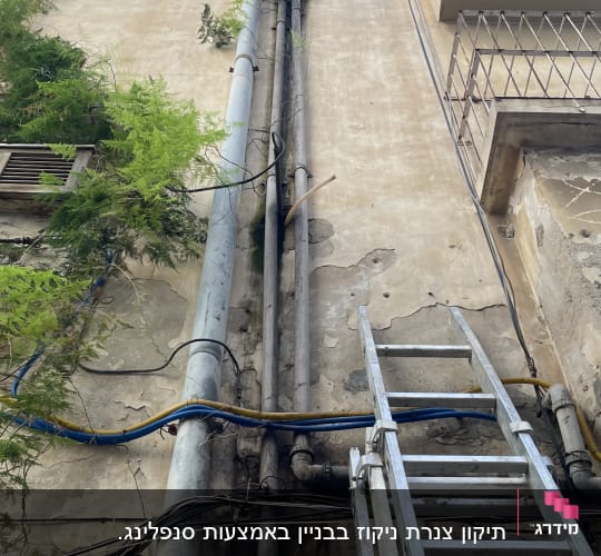 סולם מתכת ליד צינורות על קיר בניין